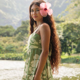 woman with brown hair wearing green tie back dress with native hawaiian plants