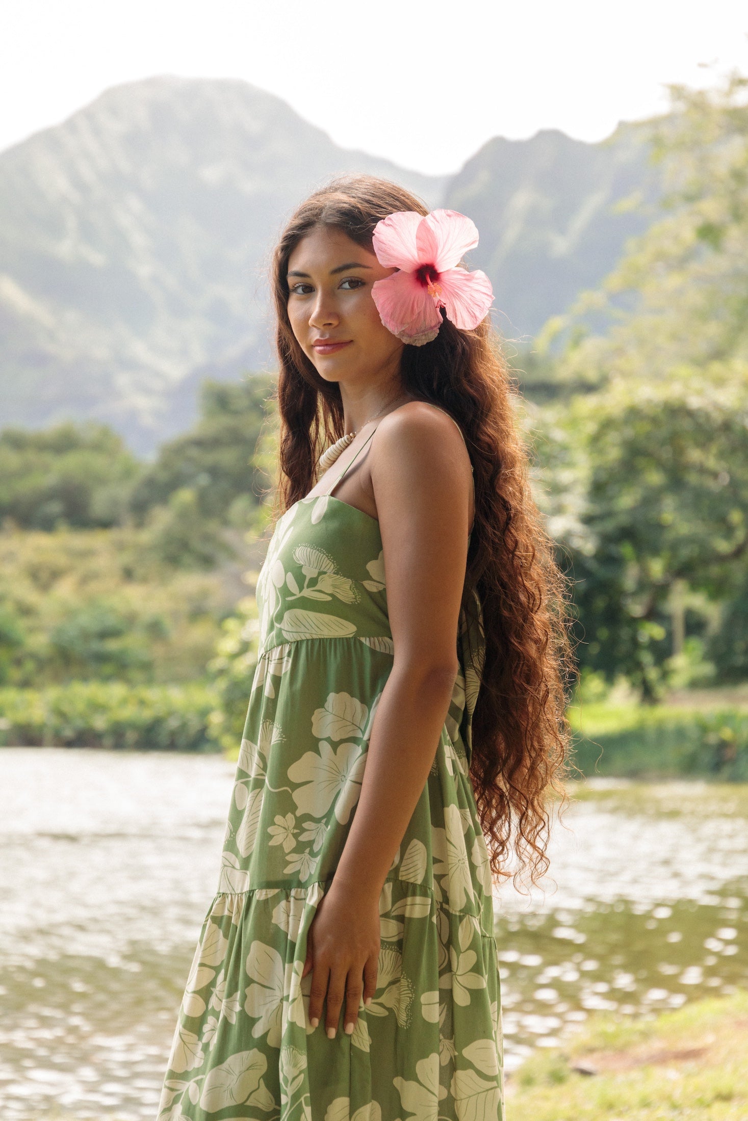 woman with brown hair wearing green tie back dress with native hawaiian plants