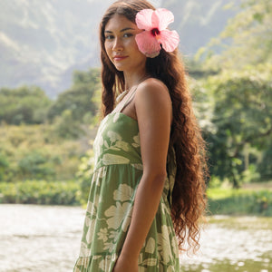 woman with brown hair wearing green tie back dress with native hawaiian plants