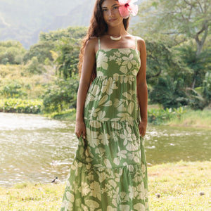 woman with brown hair wearing green tie back dress with nativr hawaiian plants
