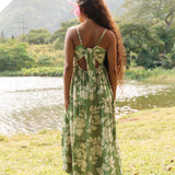 woman with brown hair wearing green tie back dress with nativr hawaiian plants
