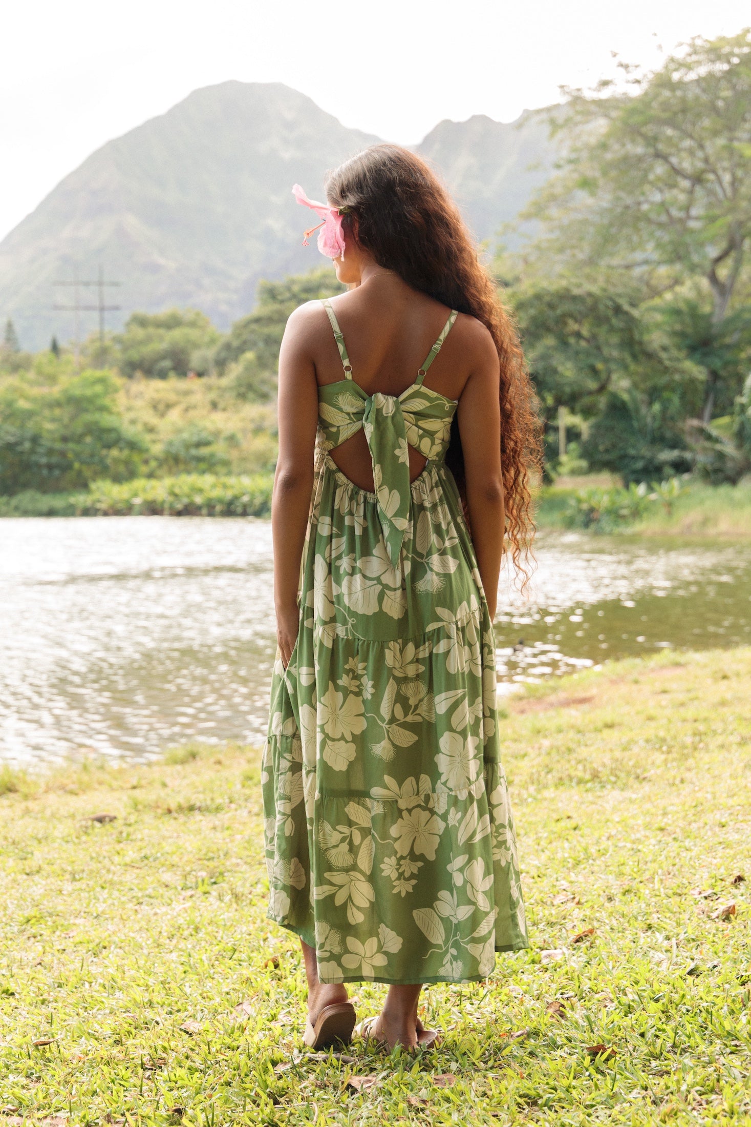 woman with brown hair wearing green tie back dress with nativr hawaiian plants