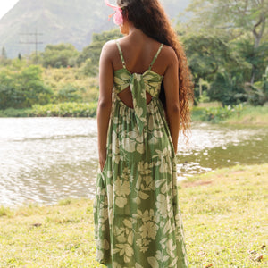 woman with brown hair wearing green tie back dress with nativr hawaiian plants