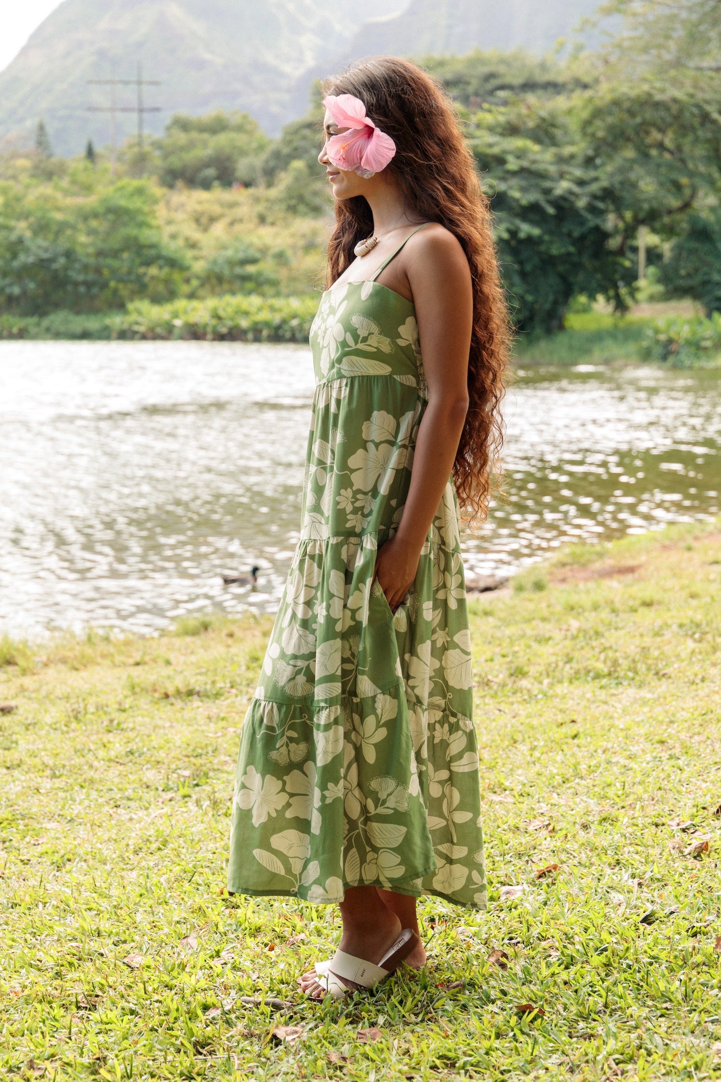 woman with brown hair wearing green tie back dress with native hawaiian plants