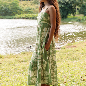 woman with brown hair wearing green tie back dress with native hawaiian plants