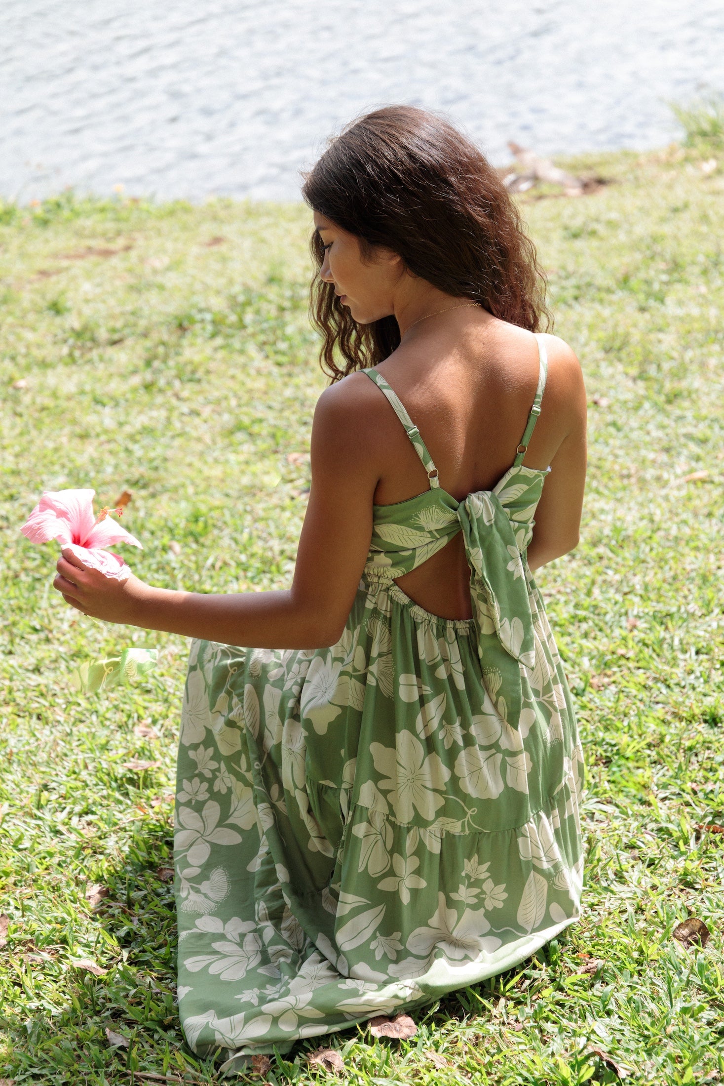 woman with brown hair wearing green tie back dress with native hawaiian plants