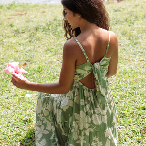 woman with brown hair wearing green tie back dress with native hawaiian plants