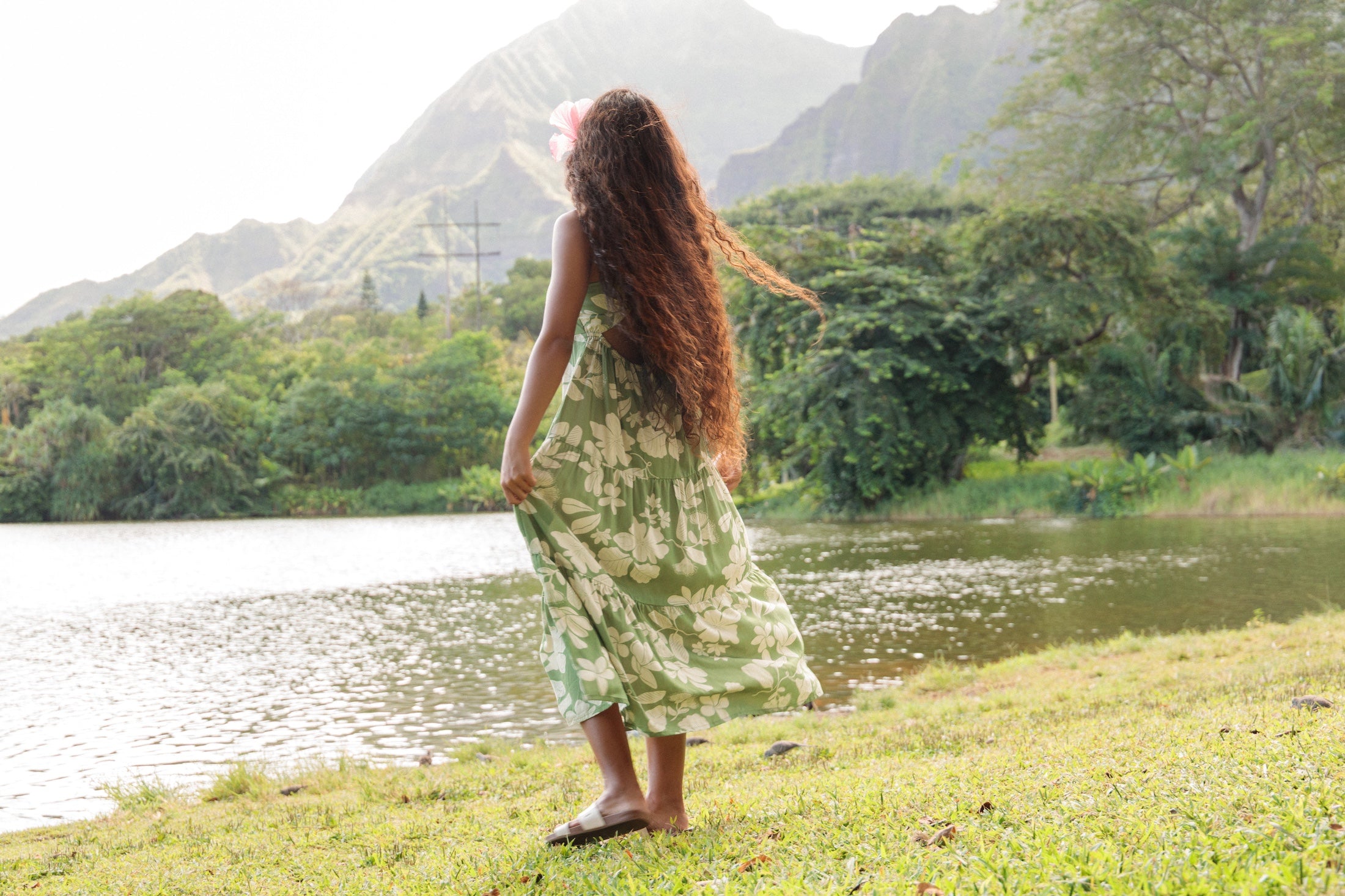 woman with brown hair wearing green tie back dress with native hawaiian plants