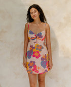 Woman in short tank dress with multi colored floral on light pink ground.