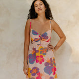 Woman in short tank dress with multi colored floral on light pink ground.