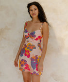 Woman in short tank dress with multi colored floral on light pink ground.