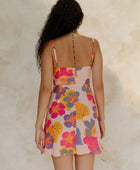 Woman in short tank dress with multi colored floral on light pink ground.