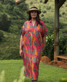 woman with brown hair wearing a colorful maxi button up dress with tropical lei print