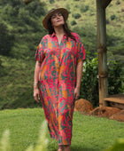woman with brown hair wearing a colorful maxi button up dress with tropical lei print