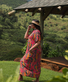 woman with brown hair wearing a colorful maxi button up dress with tropical lei print