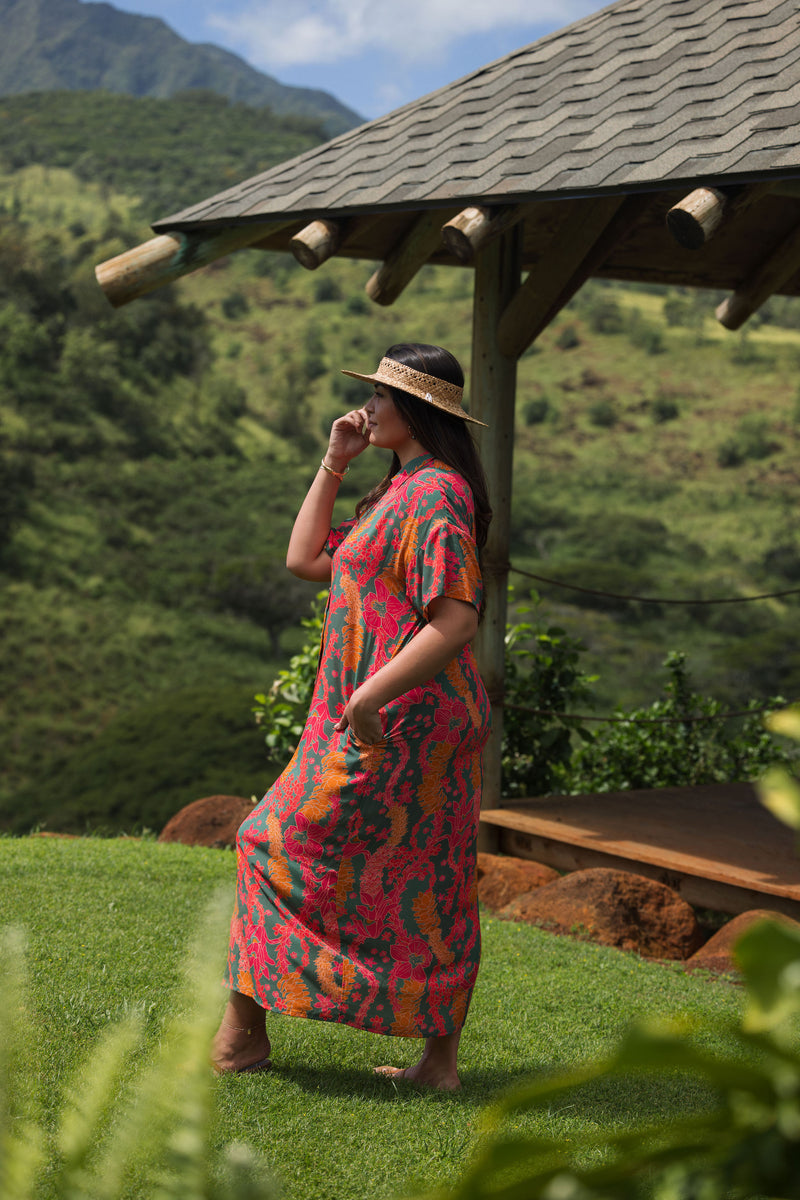 woman with brown hair wearing a colorful maxi button up dress with tropical lei print