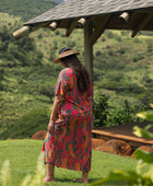 woman with brown hair wearing a colorful maxi button up dress with tropical lei print