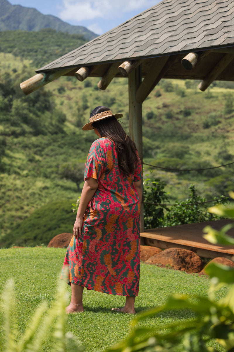woman with brown hair wearing a colorful maxi button up dress with tropical lei print