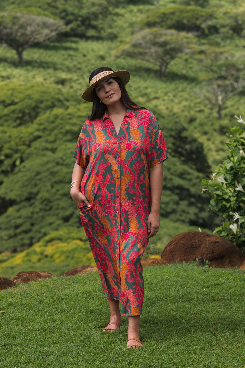 woman with brown hair wearing a colorful maxi button up dress with tropical lei print