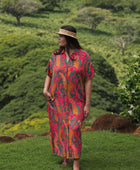 woman with brown hair wearing a colorful maxi button up dress with tropical lei print