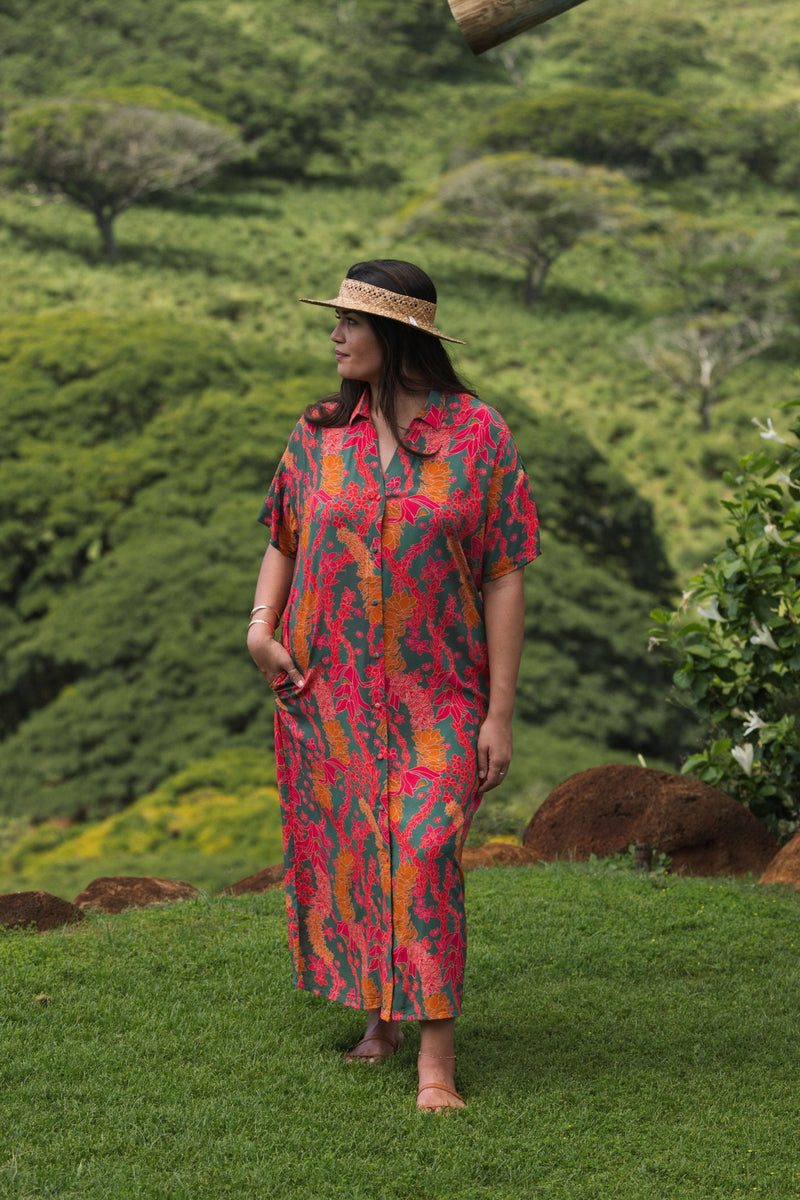 woman with brown hair wearing a colorful maxi button up dress with tropical lei print