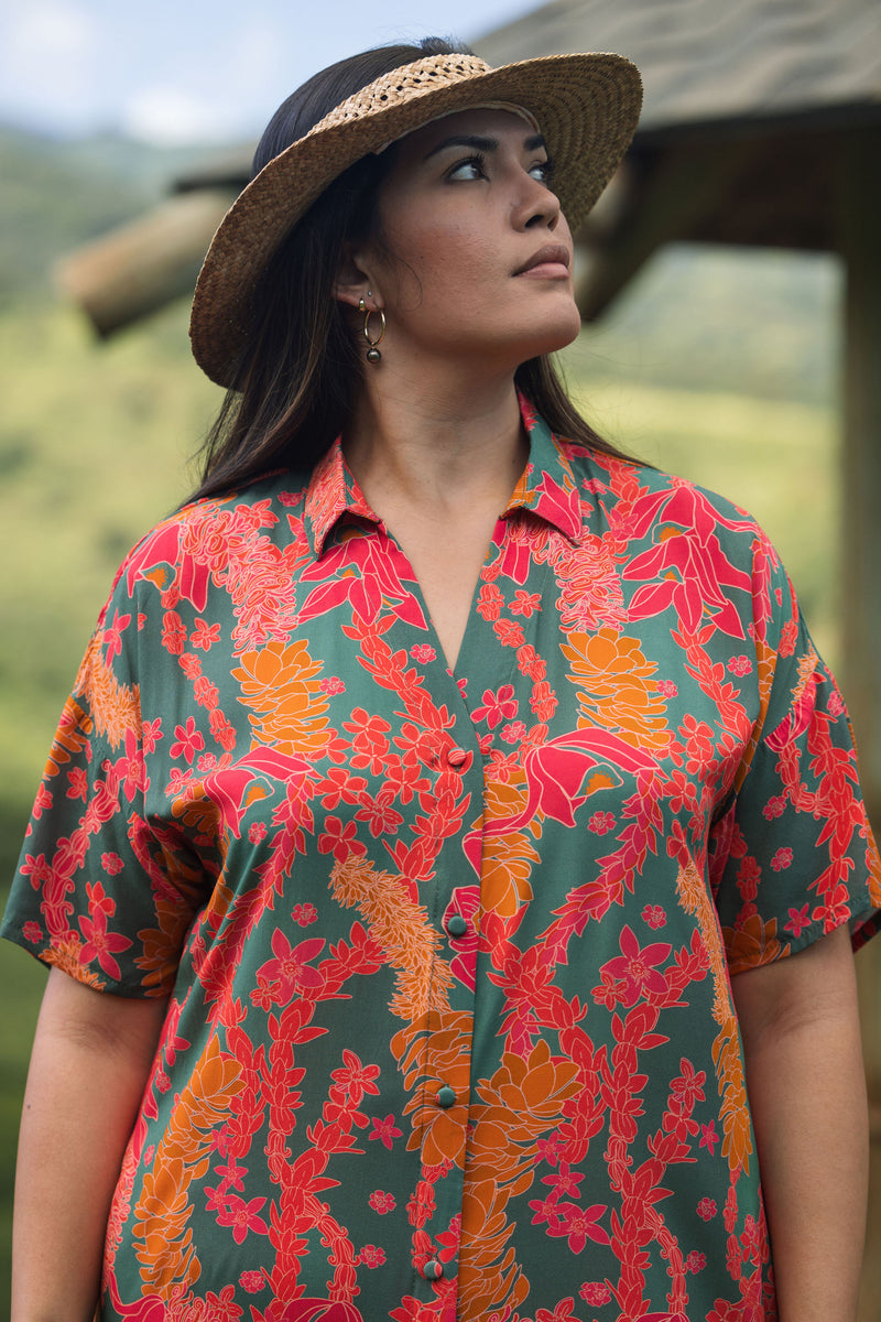 woman with brown hair wearing a colorful maxi button up dress with tropical lei print