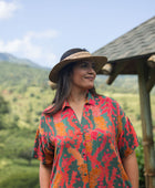 woman with brown hair wearing a colorful maxi button up dress with tropical lei print