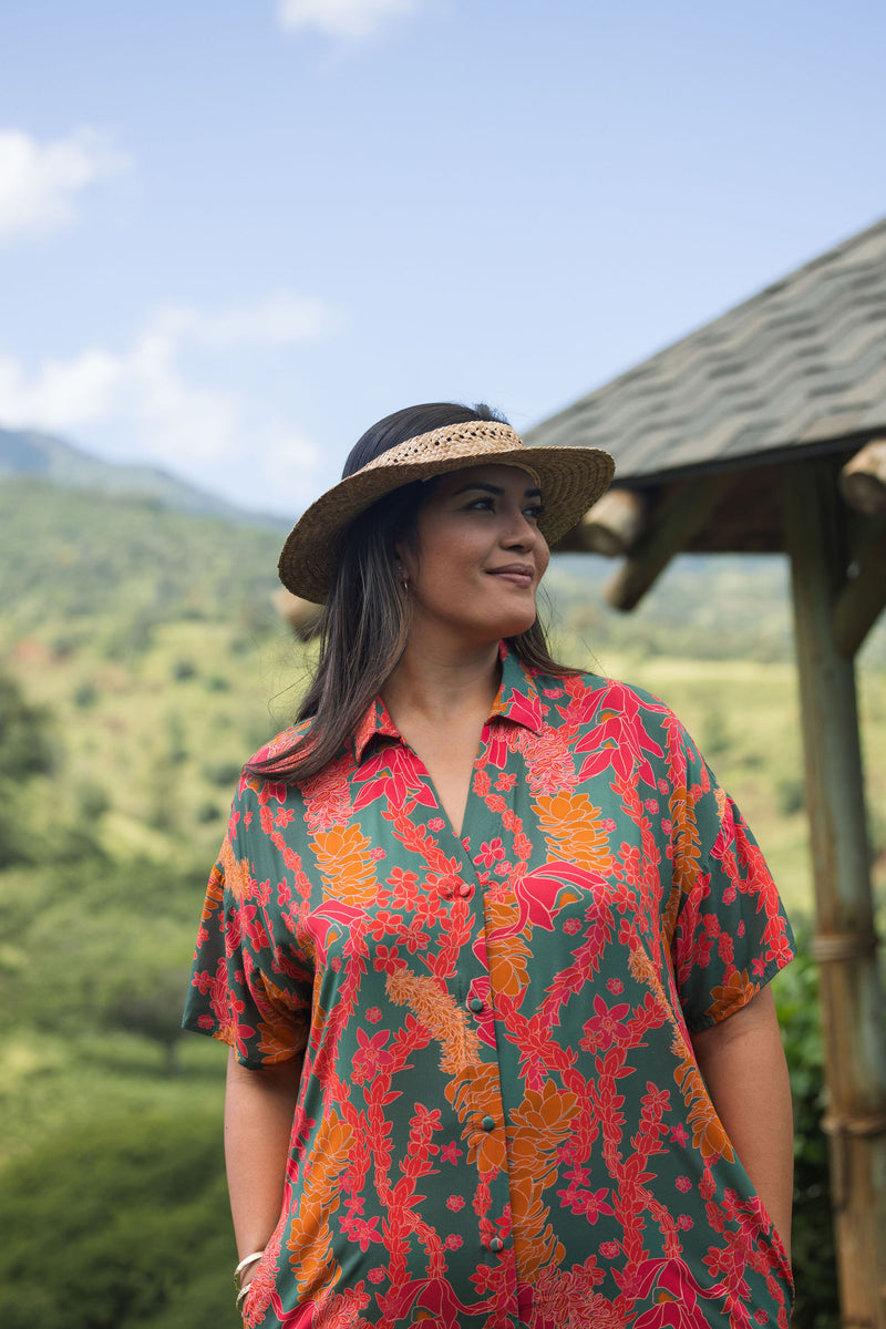 woman with brown hair wearing a colorful maxi button up dress with tropical lei print