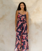 Woman in long sleeveless jumpsuit with print floral print on dark navy ground.