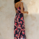 Woman in long sleeveless jumpsuit with print floral print on dark navy ground.