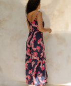 Woman in long sleeveless jumpsuit with print floral print on dark navy ground.