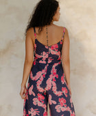 Woman in long sleeveless jumpsuit with print floral print on dark navy ground.