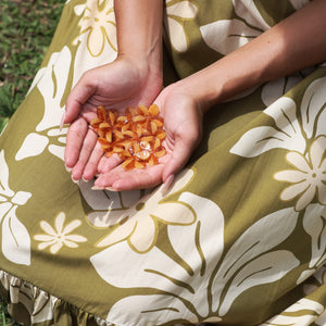 woman with brown hair wearing yellow glass plumeria necklace and earrings 