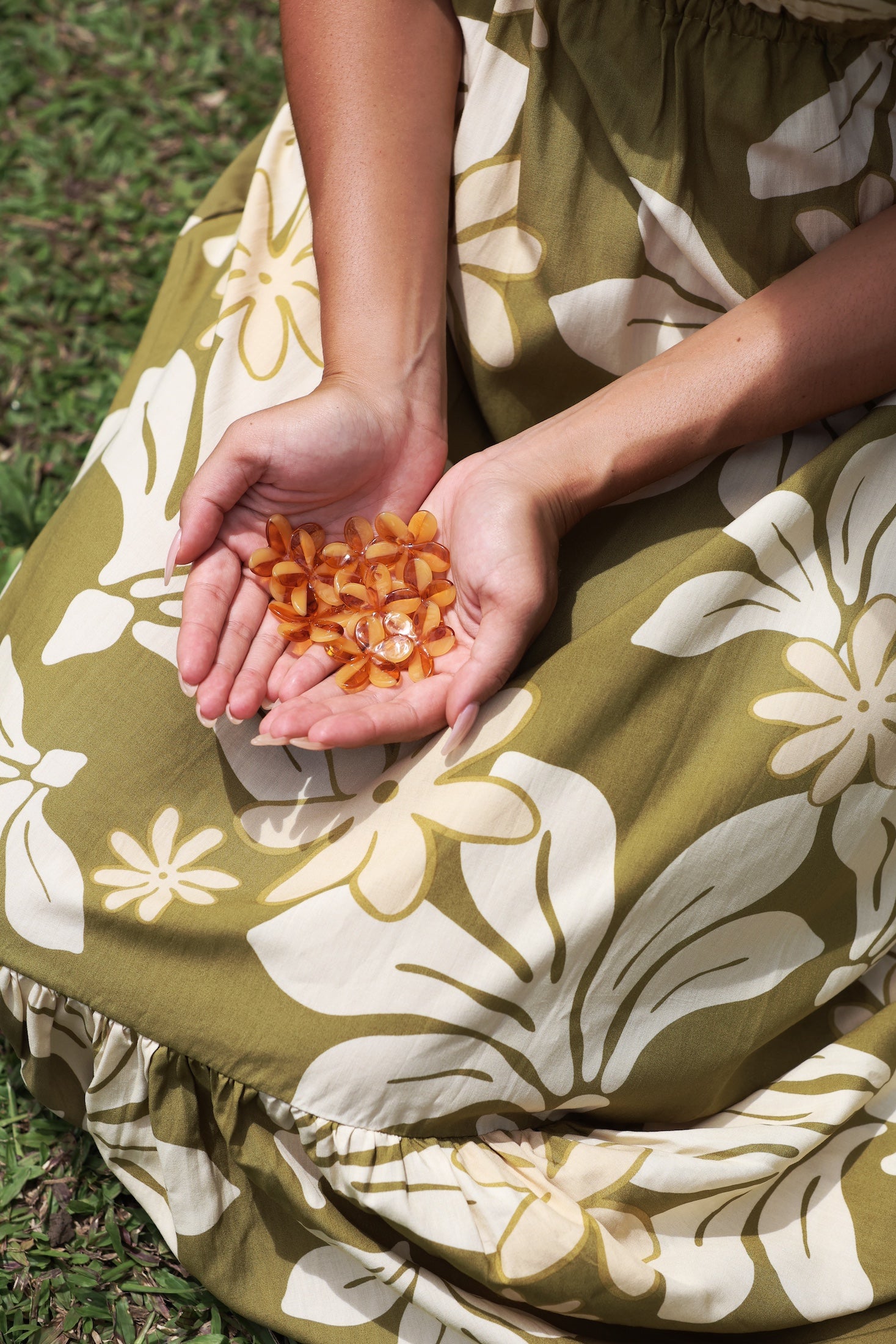 woman with brown hair wearing yellow glass plumeria necklace and earrings 