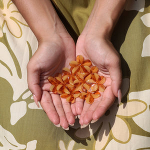 woman with brown hair wearing yellow glass plumeria necklace and earrings 