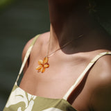 woman with brown hair wearing yellow glass plumeria necklace and earrings 