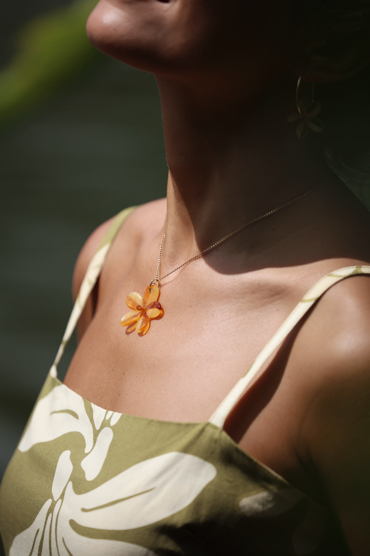 woman with brown hair wearing yellow glass plumeria necklace and earrings 