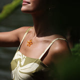 woman with brown hair wearing yellow glass plumeria necklace and earrings 