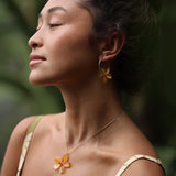 woman with brown hair wearing yellow glass plumeria necklace and earrings 