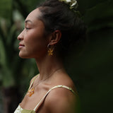 woman with brown hair wearing yellow glass plumeria necklace and earrings 