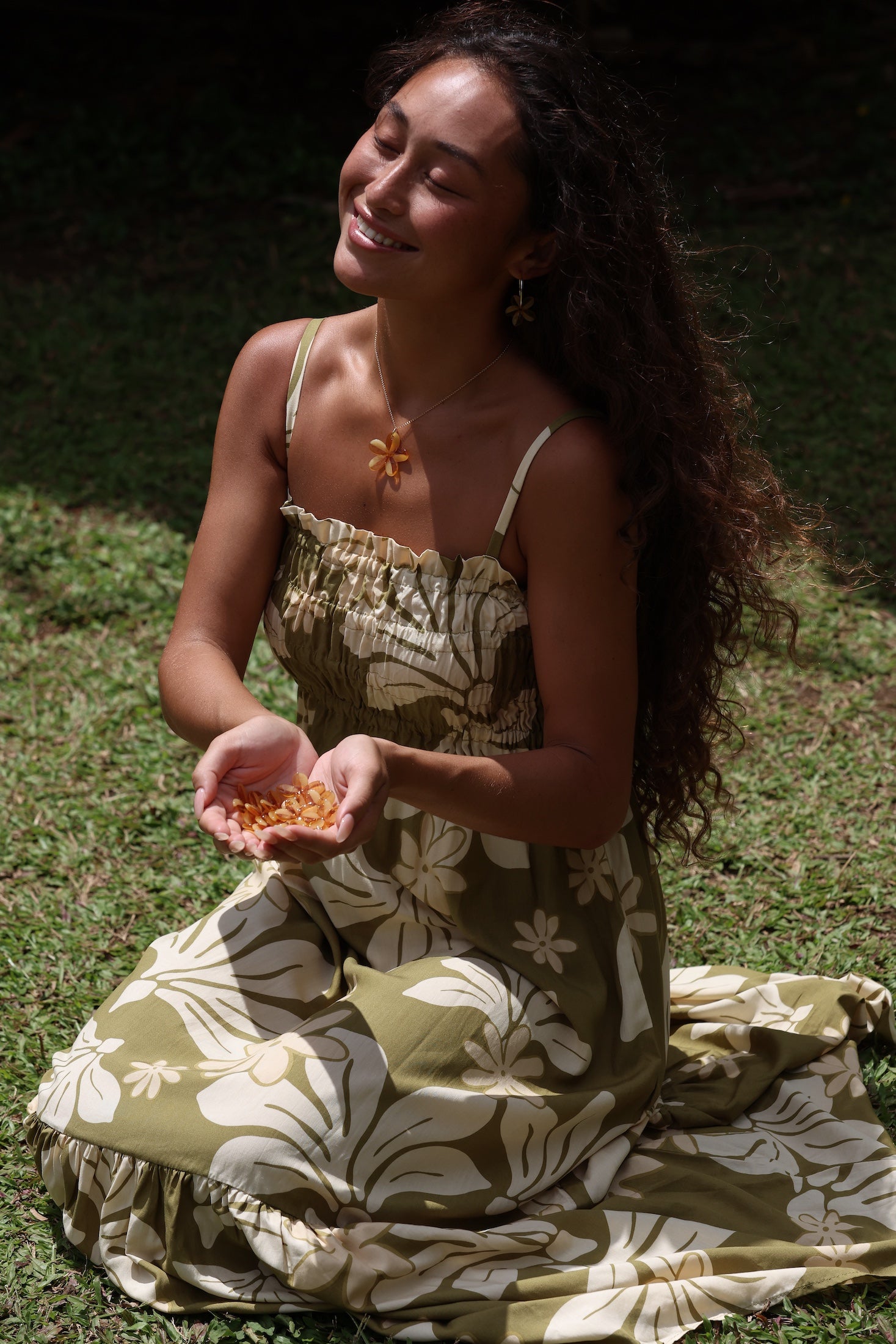 woman with brown hair wearing yellow glass plumeria necklace and earrings 