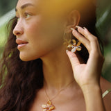 woman with brown hair wearing yellow glass plumeria necklace and earrings 