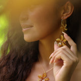 woman with brown hair wearing yellow glass plumeria necklace and earrings 