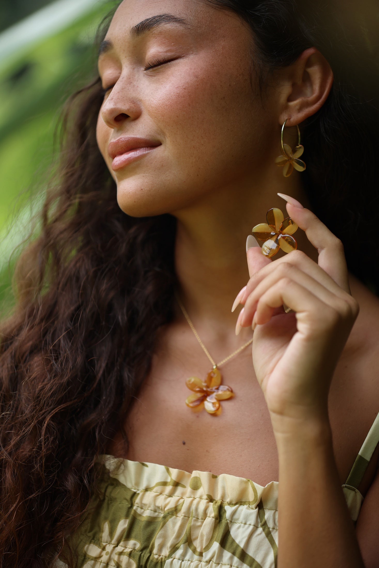 woman with brown hair wearing yellow glass plumeria necklace and earrings 