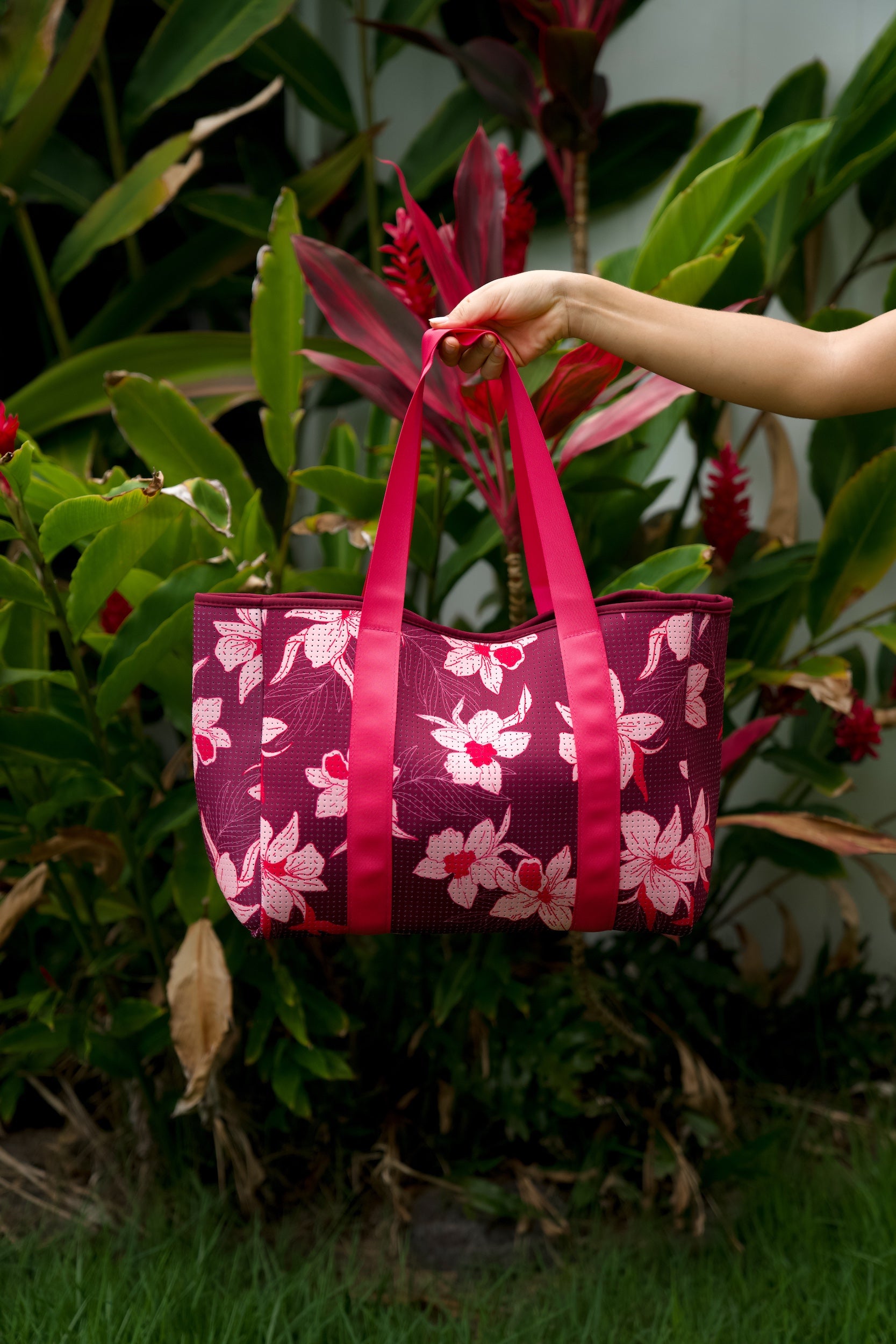 woman carrying wine colored neoprene tote bag with thick straps and detachable pouch with orchid print