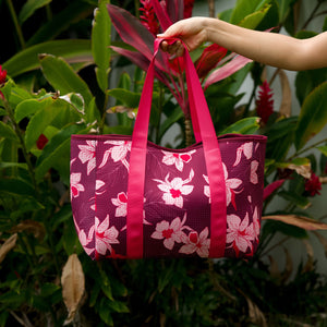woman carrying wine colored neoprene tote bag with thick straps and detachable pouch with orchid print