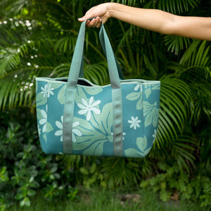 woman carrying canopy green colored neoprene tote bag with thick straps and detachable pouch with naupaka print