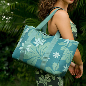 woman carrying canopy green colored neoprene tote bag with thick straps and detachable pouch with naupaka print