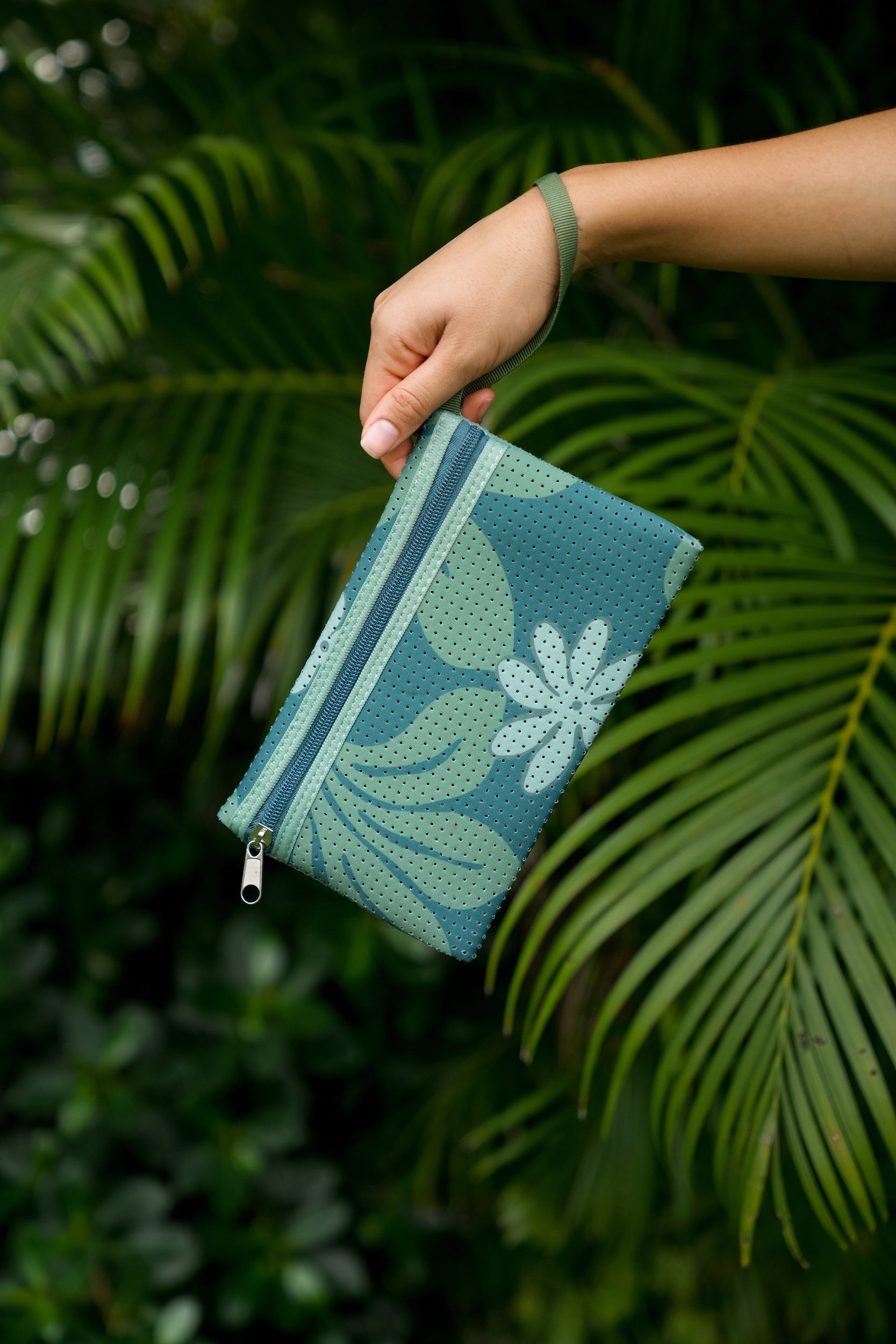 woman carrying canopy green colored neoprene tote bag with thick straps and detachable pouch with naupaka print