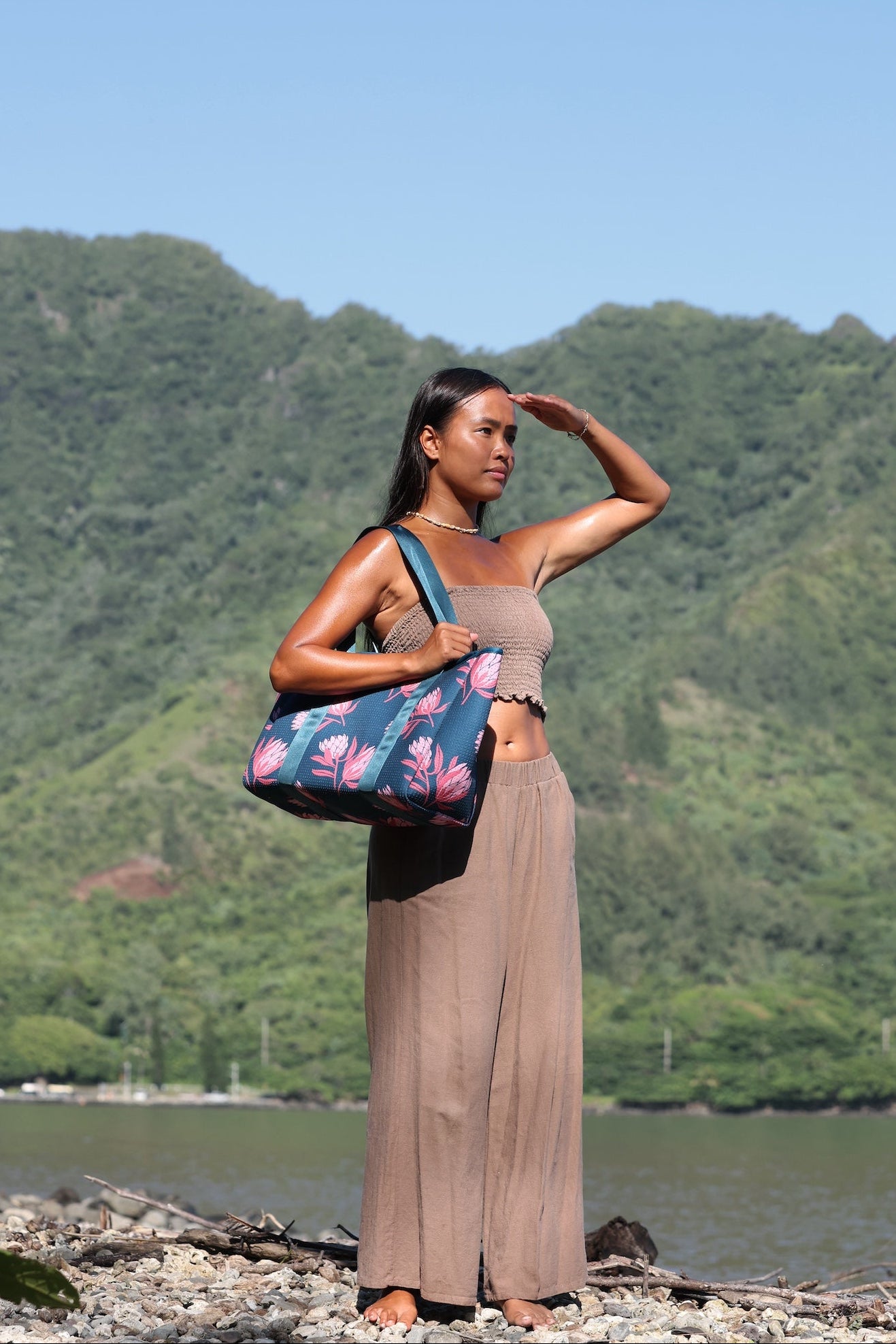 woman carrying a rich teal neoprene tote with blush colored protea print